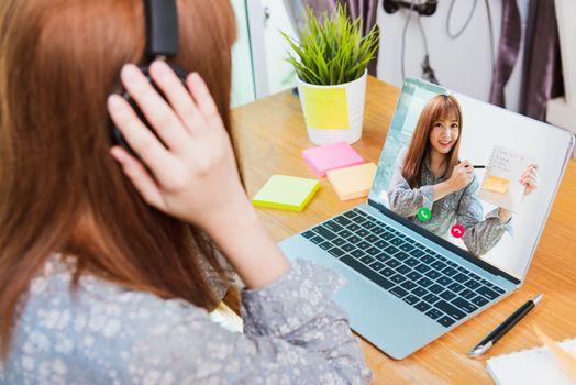 Back view of Asian business woman smart work from home using laptop computer call online to meeting talking plan in webcam video conference under curfew quarantine pandemic coronavirus COVID-19