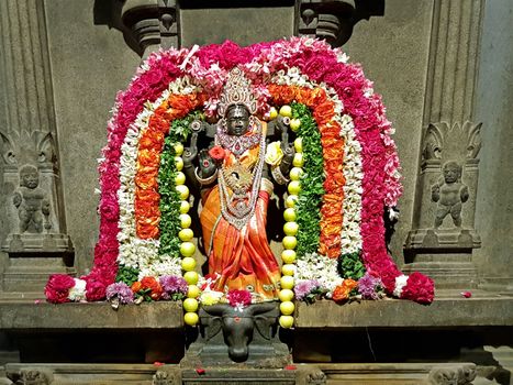 Ancient Durga statue decorated with flowers in the Sri Ramana Ashram in Tiruvanamalai India 