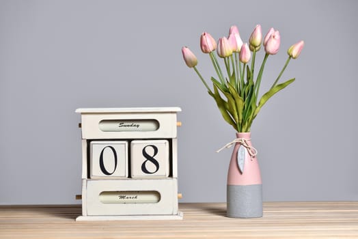 Retro calendar with the date of March 8 and tulips in a vase, International Women's Day and free text space on a gray wall background.