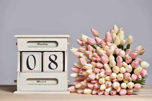 Retro calendar with the date of March 8 and tulips, International Women's Day and free text space on a gray wall background.