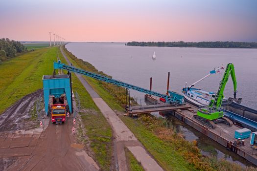 Aerial from freighter unloading sand in the countryside from the Netherlands at sunset