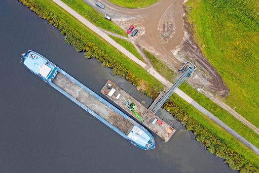 Aerial top shot from freighter unloading sand in the countryside from the Netherlands