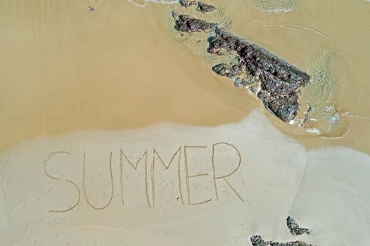 Aerial top shot from ocean waves and handwritten Summer at the beach