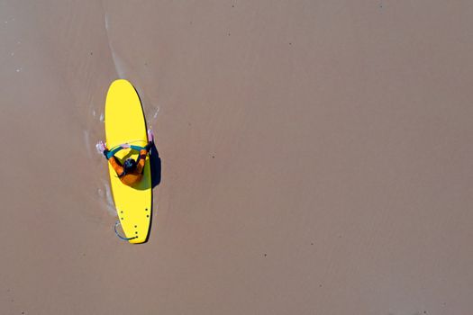 Aerial from a surfer relaxing on her surfboard at the atlantic ocean