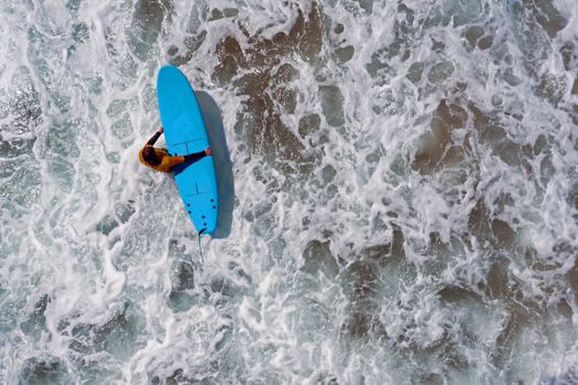 Aerial shot from a surfer going to surf in the ocean
