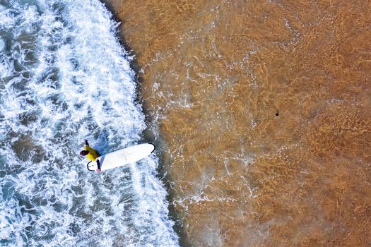 Aerial shot from a surfer going to surf in the ocean