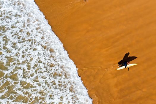 Aerial shot from a surfer coming out of the water from the atlantic ocean