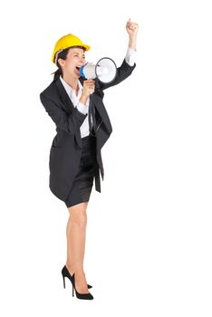 A businesswoman wearing a yellow construction helmet shouted at a megaphone while raising her fist over her head. Portrait on white background with studio light.