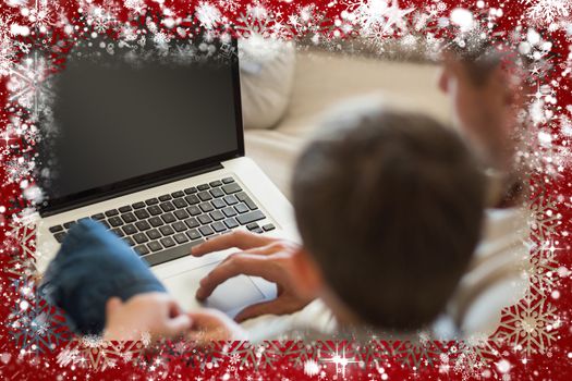 Father and son using laptop in house against snow