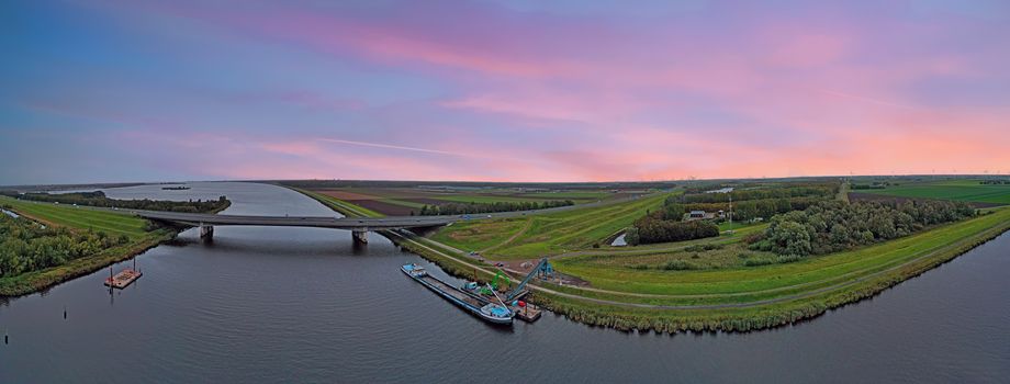 Typical dutch panoramic scenery at sunset: Highway A1 and a freighter unloading in the countryside from the Netherlands