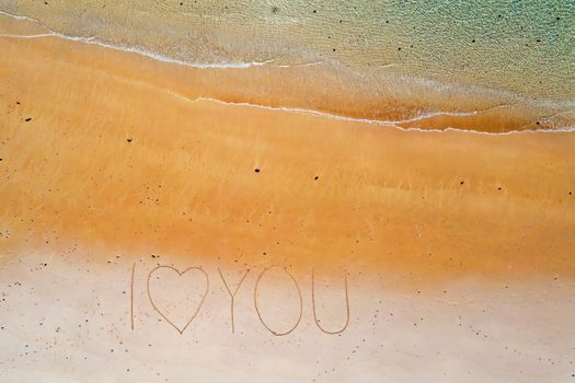 Aerial top shot from ocean waves and handwritten I love you at the beach