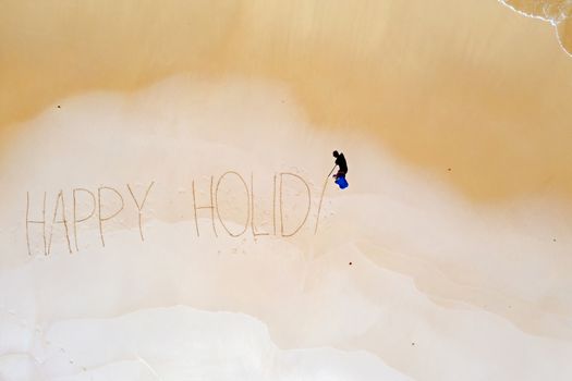 Aerial top shot from ocean waves and handwritten Happy holiday at the beach
