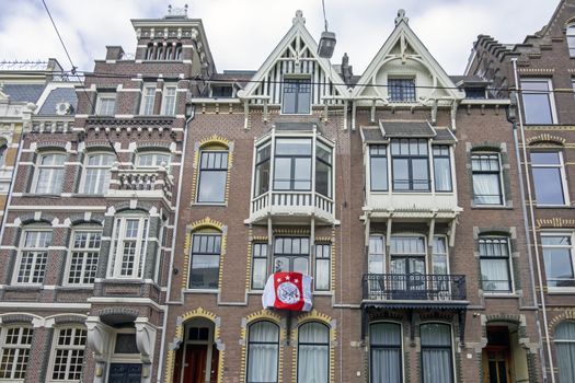 Amsterdam, Netherlands - May 16, 2019: Dutch facades with the Ajax flag honoring the national championship from Ajax in Amsterdam the Netherlands