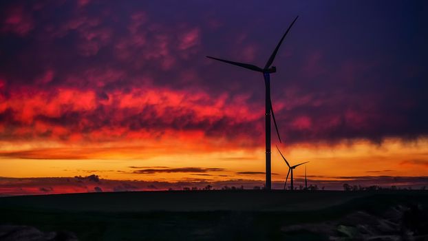 Wind generator triple set on sundown with red stripe on the sky