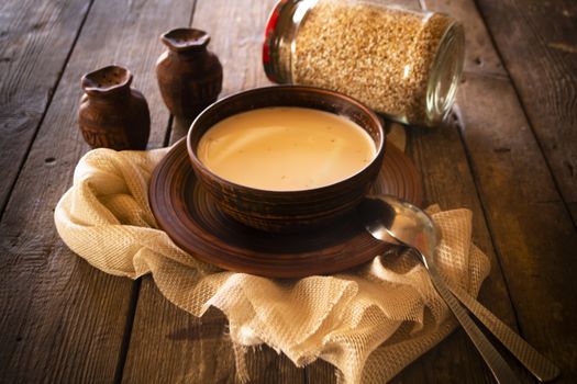 Boiled buckwheat with milk in wooden bowl on rustic wooden table