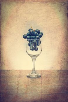 Conceptual idea of grapes in the wine glass as raw material instead of  final product using a vintage filter
