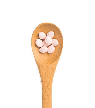 pills in wooden spoon isolated on white background