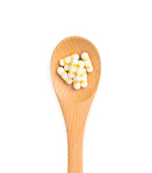 pills in wooden spoon isolated on white background