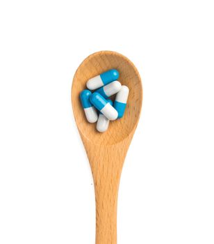 pills in wooden spoon isolated on white background