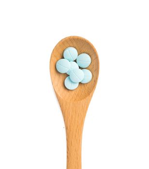 pills in wooden spoon isolated on white background