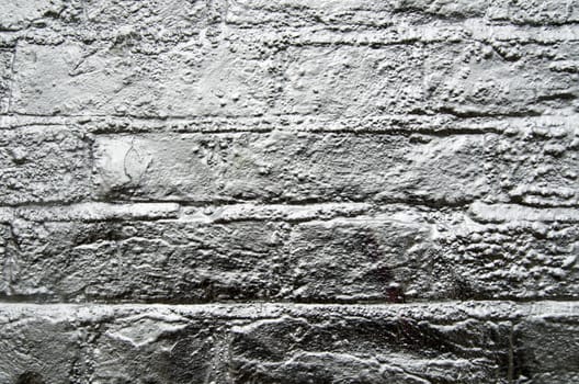 A brick wall sprayed with silver paint.