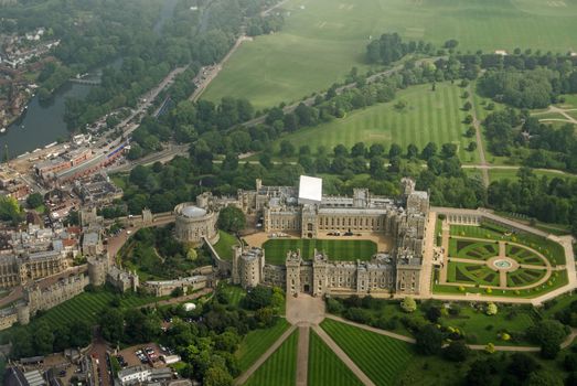 View from a plane of the historic Windsor Castle, home of Queen Elizabeth II in Royal Berkshire.  The River Thames passes to the left hand side and castle grounds stretch to the edge of the image.  Cloudy Summer morning in June 2016.