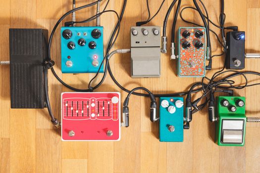 Guitar pedalboard on the floor of a recording studio. Generic guitar effects on the wooden floor. Guitar recording, rock music creation concept