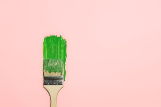 Paintbrush and a trail of green paint in isolated background. Concept of painting, renovation, home and household chores