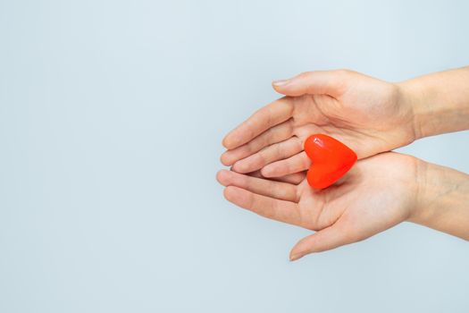 Female hands hold heart shape in palms on white background with copy space. Concept of heart disease and heart health care. St. Valentine's day concept