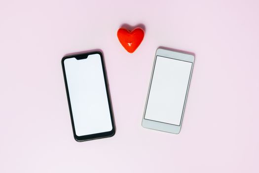Two phones with white screens and a heart. Messaging, love texting and online dating concept