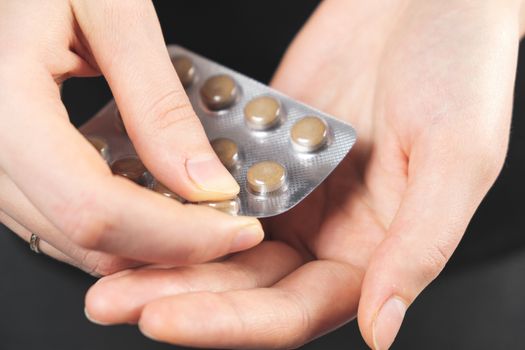 Taking medical pills or prescription drugs. Close-up view of a blister with medicine in human hand