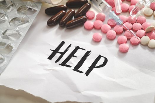 Word "help" in the pile of pills, tablets and syringes. Concept of substance abuse, drug overdose or illegal drugs dependancy