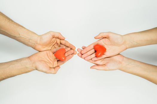 Female and male hands hold heart figures in palms on white background with copy space. Concept of charity, couples , relationships, love. St. Valentine's day concept
