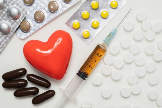 Heart and pills with syringe on white background, top view. Cardiology, heart disease concept.