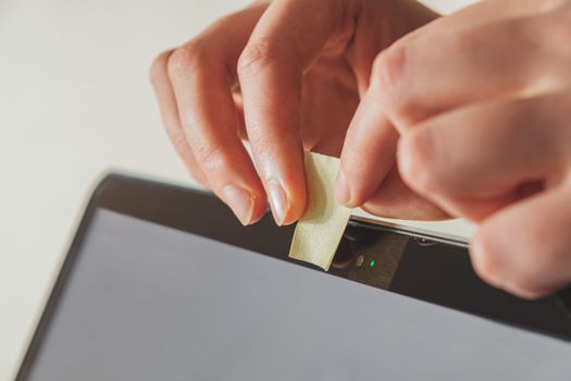 Putting a piece of sticky paper on a computer webcam. Concept of privacy, online security or safety with using a computer to prevent spying