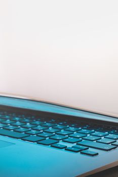 Close-up view of backlit laptop keyboard and blue light from the screen. Closed lid of a portable computer, concept of private information, not safe for work concept