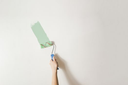 Hand with a paintbrush against the white wall. Redecorating, renovating the room or the living space