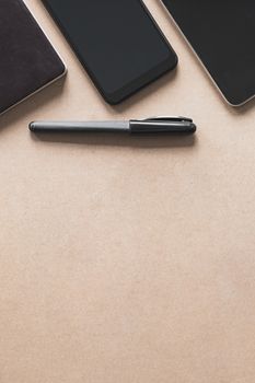 Business flat lay on brown paper background. Smartphone, tablet computer and notebook organizer on vintage background