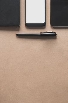 Business flat lay on brown paper background. Smartphone, tablet computer and notebook organizer on vintage background