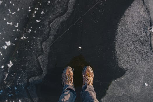 Standing on the thin ice, top view. Human feet on beautiful textured ice on the lake or river