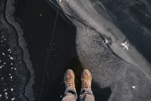 Standing on the thin ice, top view. Human feet on beautiful textured ice on the lake or river