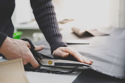 Hands of a male worker cut fabric with large scissors. Hand labor, handcrafting goods, doing small business