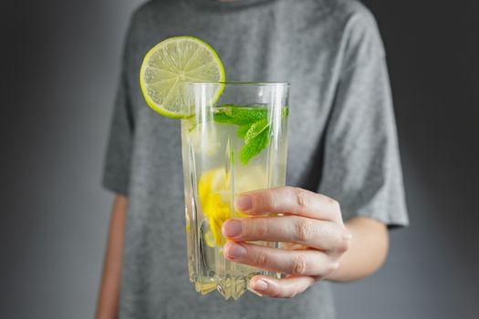 Glass of lemon drink in a human hand. Hangover cure, tonic water or mojito refreshment