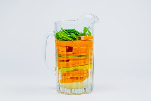 Large glass jar with citrus fruit and mint in white background. Lemonade with oranges, lime and lemons. Healthy and vitamins rich fruit drink