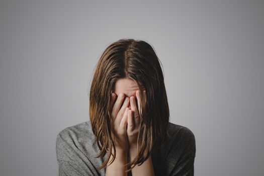 Woman covers face in hands. Concept of despair, depression, loss or mental condition