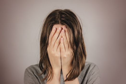 Woman covers face in hands. Concept of despair, depression, loss or mental condition