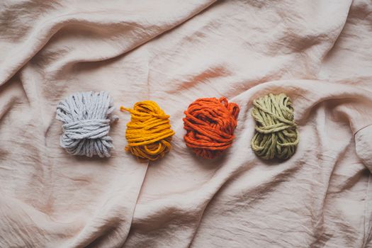 Macrame ropes in various colors, top view. Mustard, red, olive and white crochet threads in beautiful pastel backdrop, flat lay image