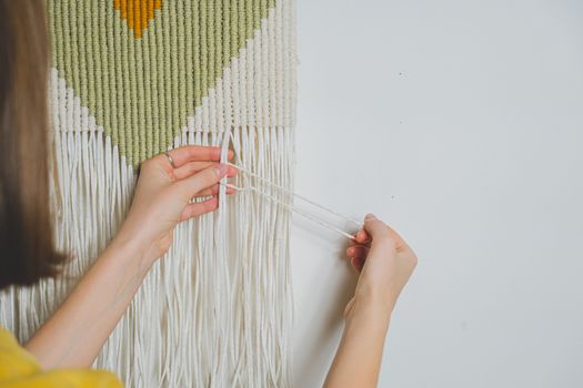 Woman doing macrame craft. Hand-making a cotton rope wall-hanging decor piece, concept of handicraft hobby or handworking