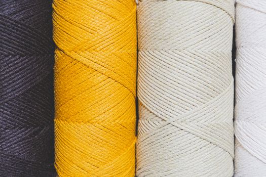 Macrame threads, close-up texture view. Rolls of crochet ropes in black, yellow and mint colors, macro shot