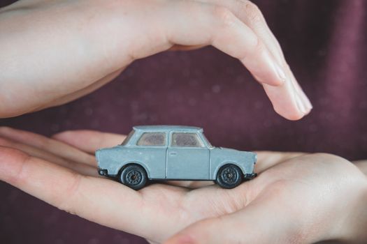 Toy car in human hands. Concept of car safety, vehicle  insurance plans or preserving old cars